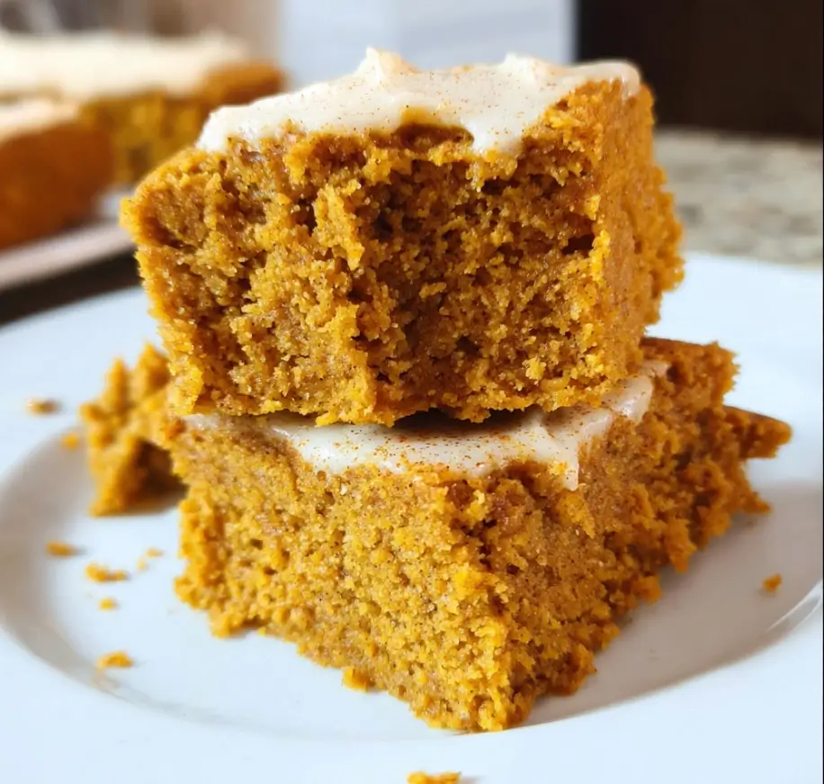 Healthy Pumpkin Bars with Cream Cheese Frosting 6 Two stacked healthy pumpkin bars with cream cheese frosting on a white plate