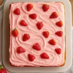 Delicious strawberry sheet cake topped with fresh strawberries and cream