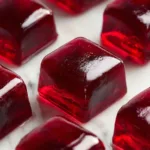 Close-up of jillian michaels gelatin gummies in silicone mold, ruby-red color, glistening surface