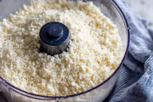 Riced cauliflower in a food processor bowl with a coarse rice-like texture , cauliflower pizza crust